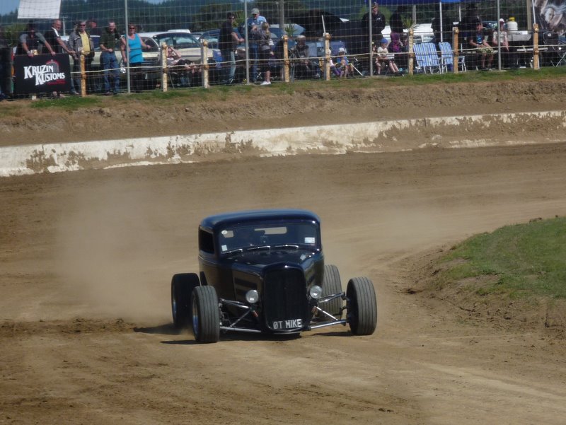 Black hot rod with license plate 'BT MIKE' on a dirt track