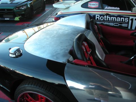 1998 Ford Crown Victoria - polished black decklid of a sports car in the foreground, with a white Rothmans-Porsche-liveried race car parked just behind it.