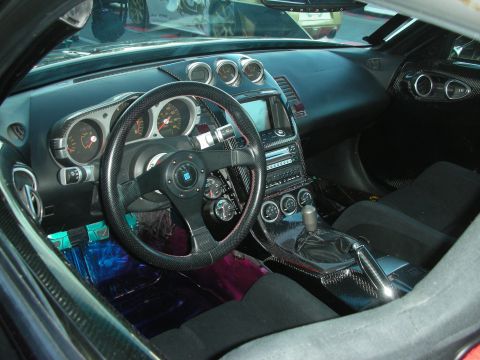 1998 Ford Crown Victoria - interior of a Nissan 350Z featuring carbon-fiber trim, a deep-dish steering wheel, Z badge, and triple-pod top gauges.