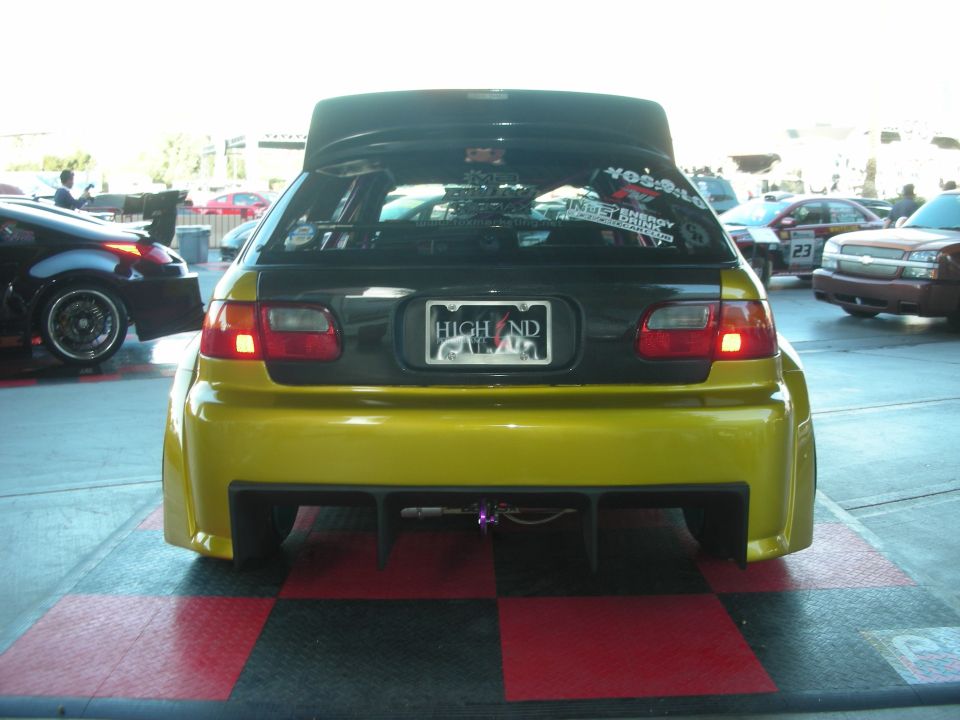 Yellow hatchback rear with large wing, diffuser and HIGH END plate at outdoor show
