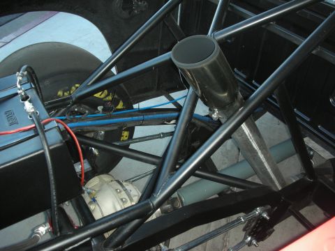 1998 Ford Crown Victoria - Detail of a black tubular space-frame chassis showing roll-cage tubing, braided brake lines and a polished rear-axle housing.