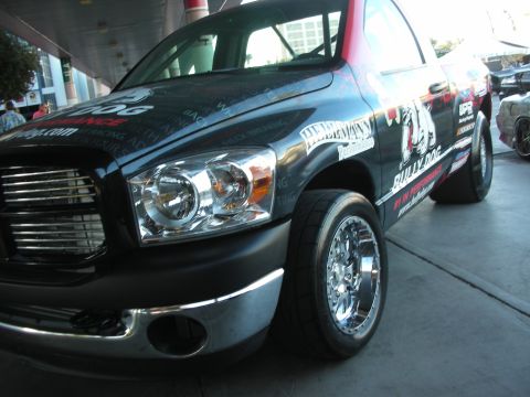 1998 Ford Crown Victoria - Low front-corner shot of a dark Dodge Ram pickup with a sponsor graphics wrap, chrome multi-spoke wheel and drag radial tire.