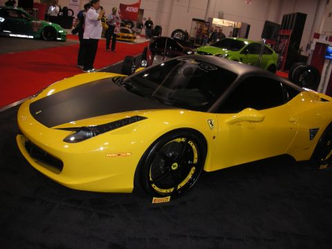 1998 Ford Crown Victoria - Front three-quarter view of a yellow Ferrari 458 with a satin-black hood and black wheels with yellow lips on a Pirelli tire display.