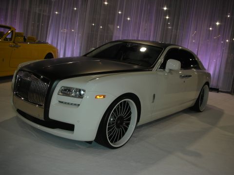 1998 Ford Crown Victoria - white Rolls-Royce Ghost with a satin-black roof and bonnet, displayed on large chrome multi-spoke wheels against a purple-lit drape.
