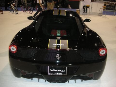 1998 Ford Crown Victoria - Rear view of a black Ferrari 458 with gold dual racing stripes and a red engine bay, on a show stand with a Giovanna license-plate frame.