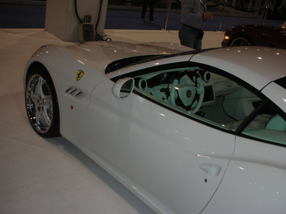 Side profile of white Ferrari coupe with light interior and chrome wheels