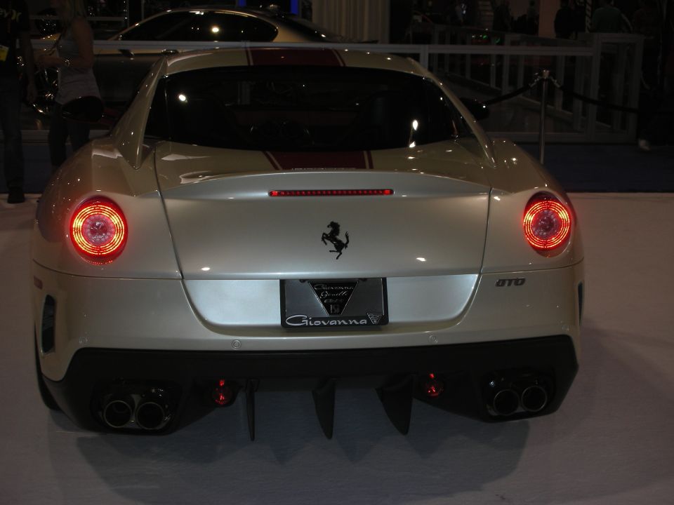Rear of silver Ferrari 599 GTB with red center stripe and quad taillights at car show