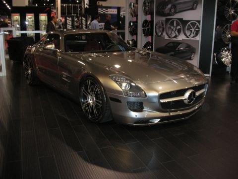 1998 Ford Crown Victoria - silver Mercedes-Benz SLS AMG coupe with a long hood and large multi-spoke wheels parked in a wheel-display booth.