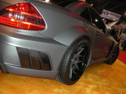 1998 Ford Crown Victoria - Close-up of a matte-gray widebody Mercedes coupe showing the rear taillight, carbon-fiber fender vents and a large black multi-spoke wheel.