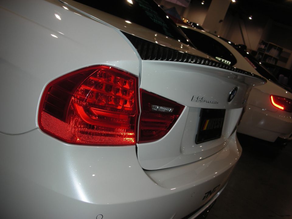Close-up of white BMW sedan rear corner showing LED taillight and trunk emblem