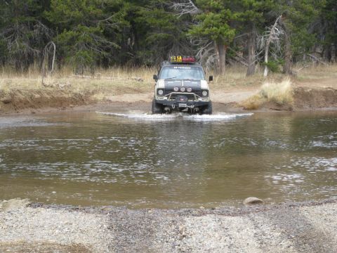1986 Ford Bronco - This modified Ford Bronco navigates a shallow stream in a wooded area.