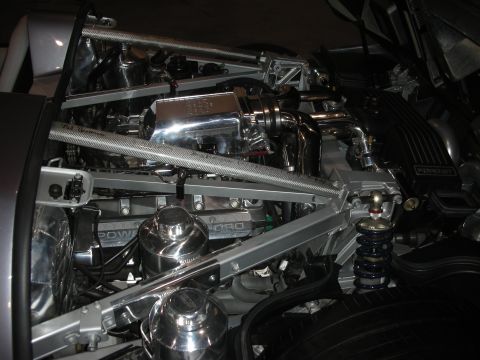 1998 Ford Crown Victoria - exposed engine and rear suspension of a Ford GT, showing polished components, carbon-fiber braces, a Ford cam cover and blue coilover shock…
