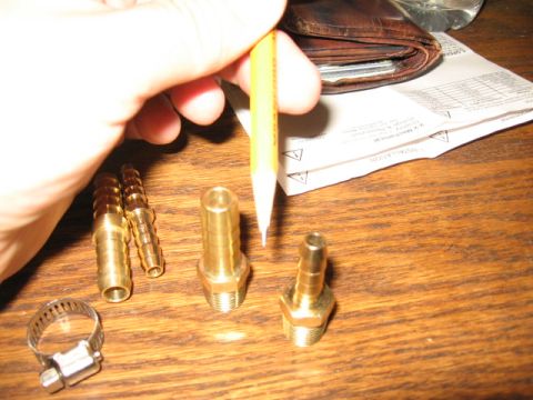 1995 Ford Bronco - Several brass hose fittings and a hose clamp are laid out on a wooden table.