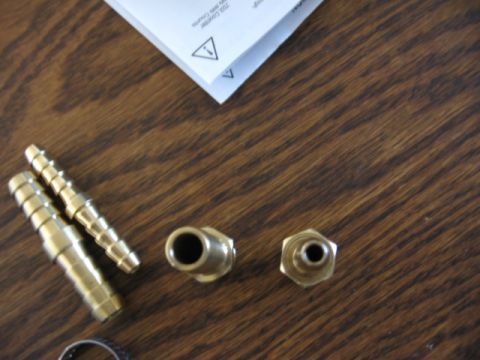 1995 Ford Bronco - Several brass fittings, likely for an air system, are laid out on a wooden table next to a document.