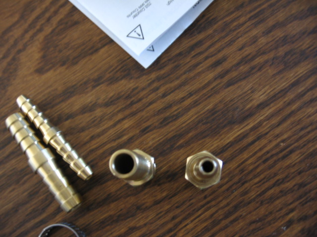Brass hose barb and threaded fittings on dark wood with an instruction sheet