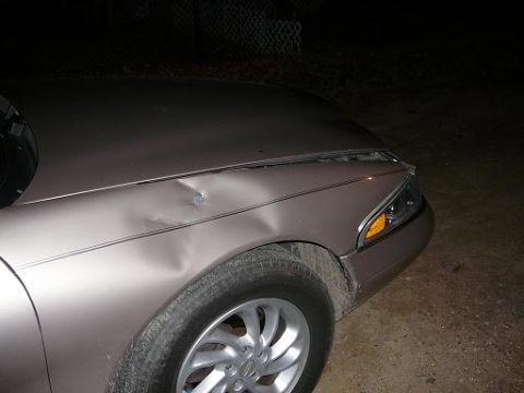 1997 Lincoln Mark VIII - The front passenger side of a car shows significant damage to the fender and hood area.