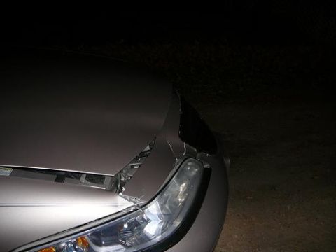 1997 Lincoln Mark VIII - A damaged silver car's front end is visible at night, with the hood crumpled and a headlight broken.