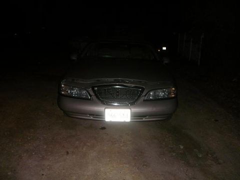 1997 Lincoln Mark VIII - The front end of a Lincoln Mark VIII is illuminated by headlights at night, showing its grille and license plate.