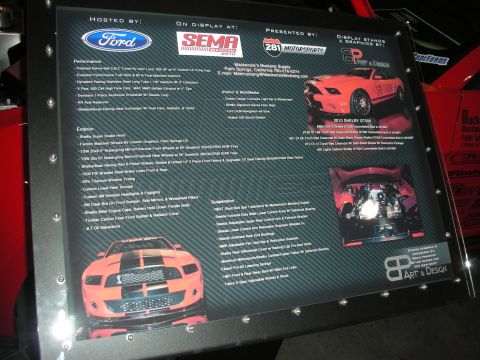 1998 Ford Crown Victoria - red Mustang engine bay with a chrome supercharger, red cone air filter and carbon-fiber radiator cover, hood raised at a show.