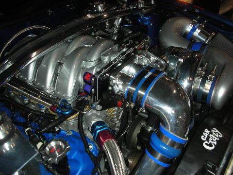 1998 Ford Crown Victoria - blue-accented engine bay with a silver intake manifold, polished supercharger, chrome piping and a Car Crazy plaque.