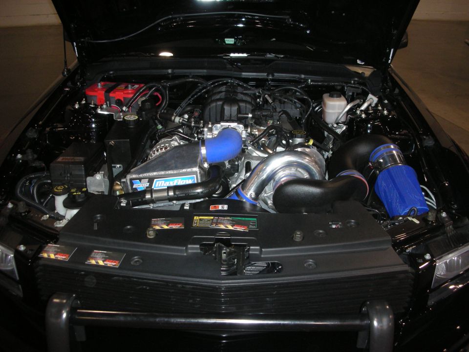 Black car engine bay with supercharger, blue intake and MaxFlow cover