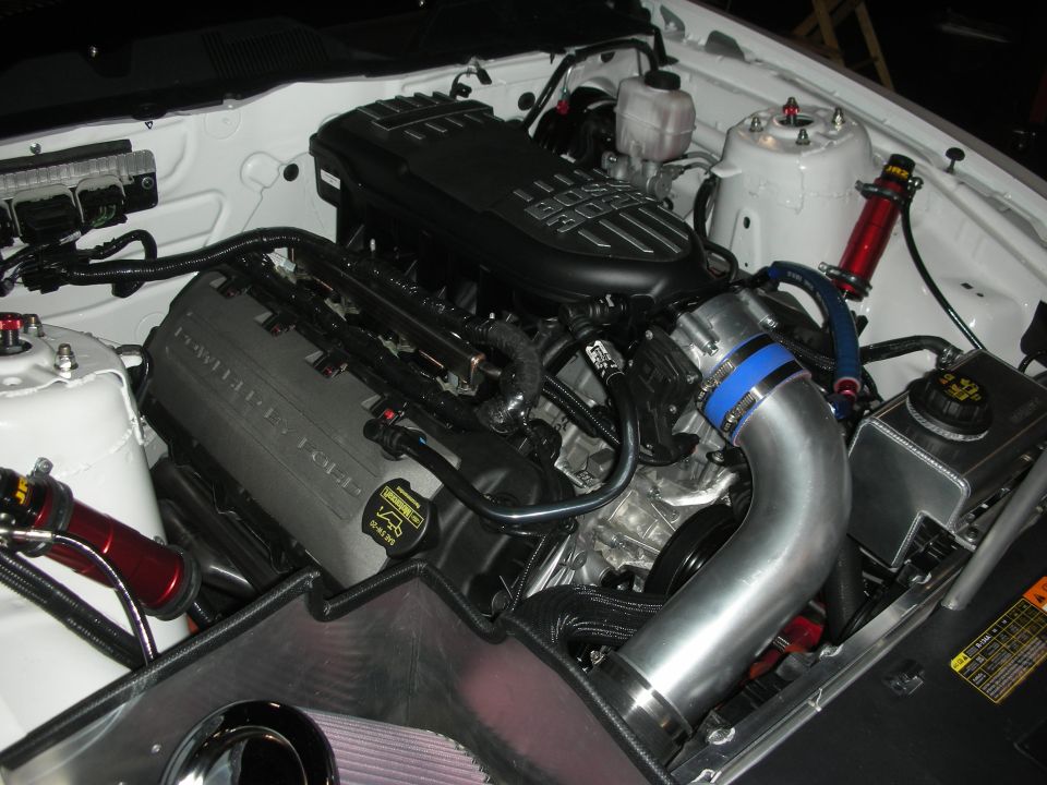 Supercharged engine with cast valve cover in a white-painted engine bay
