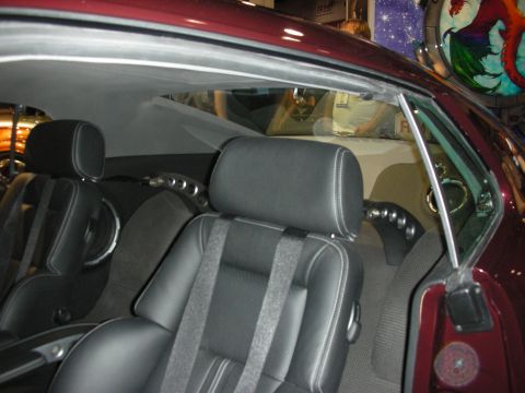 1998 Ford Crown Victoria - Interior view through the side window of a maroon coupe showing black leather bucket seats with contrast stitching.