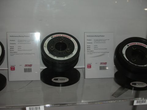 1998 Ford Crown Victoria - Black ATI Super Damper harmonic balancers displayed on a glass shelf beside printed SEMA performance-product information cards.