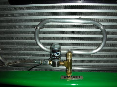 1998 Ford Crown Victoria - aluminum front-mount intercooler with a looped pipe and a small solenoid valve, mounted above a green panel with a ZeroSports badge.