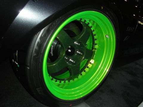 1998 Ford Crown Victoria - Detail of a green-finish forged wheel with visible lip bolts and a low-profile tire mounted on a dark show car.