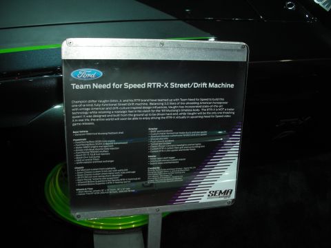 1998 Ford Crown Victoria - illuminated Ford placard describing the Team Need for Speed RTR-X street/drift machine, with green wheels visible behind it.