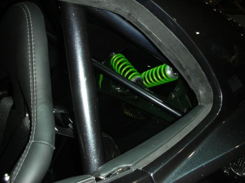 1998 Ford Crown Victoria - View through a black roll-cage tube past a racing seat to a green-spring coilover shock mounted in the car's rear.