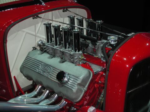 1998 Ford Crown Victoria - Close-up of a vintage Ford V8 engine fitted with tall chrome velocity-stack intakes in a red hot rod roadster.