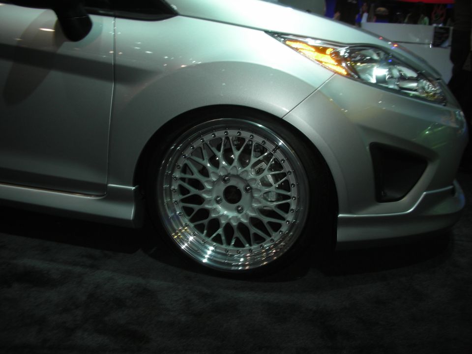 Silver hatchback front wheel with mesh wheel and body kit at show