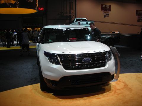 1998 Ford Crown Victoria - Front view of a white Ford Explorer SUV with a black mesh grille on a display platform at an indoor automotive show.