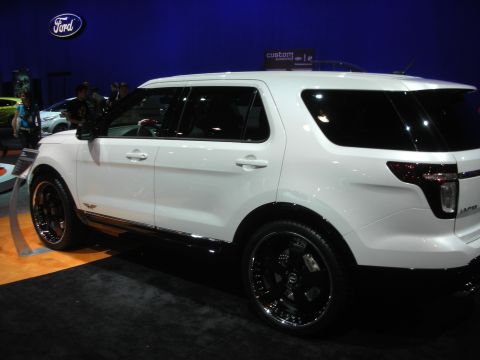 1998 Ford Crown Victoria - Rear three-quarter view of a white Ford Explorer SUV fitted with large black and chrome wheels at an indoor display.