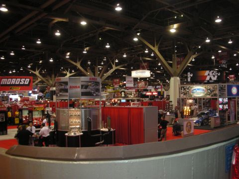 1998 Ford Crown Victoria - Wide overview of a large indoor automotive trade show floor with numerous vendor booths including Moroso and K&N under high ceilings.
