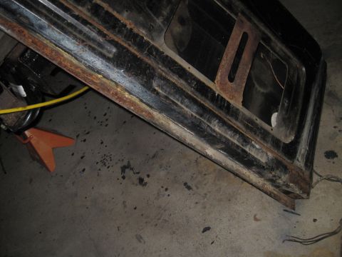 1979 Ford Bronco - Close-up of a heavily rusted black metal body panel, possibly from a vehicle's rear section.