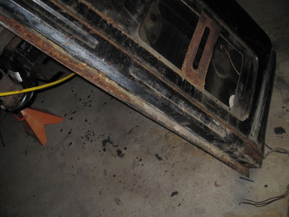 Rusted black metal body panel with window opening