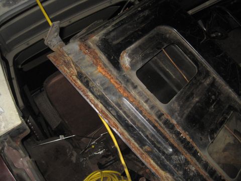 1979 Ford Bronco - The heavily rusted door frame of a 1979 Ford Bronco is visible, with a yellow cable running across it.