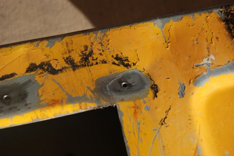 1982 Ford Bronco - Close-up of a yellow painted metal panel showing signs of wear and repair.