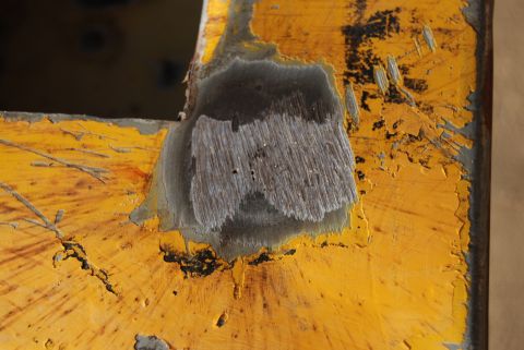 1982 Ford Bronco - Detail of weathered yellow metal showing a rough, wood-like texture where paint has chipped away.