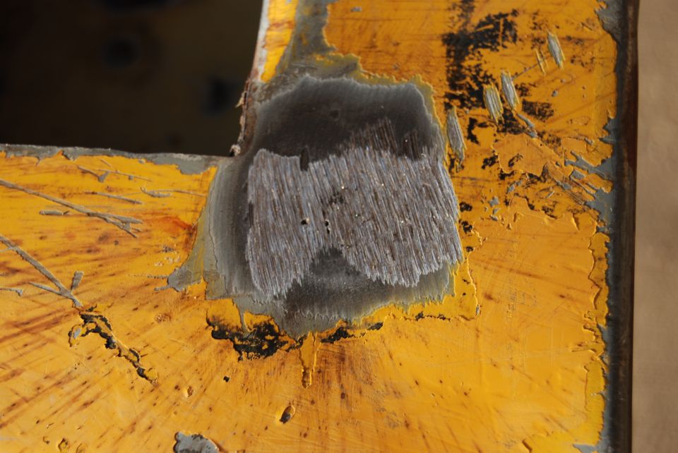Close-up of worn yellow metal with exposed wood-like texture