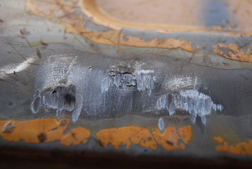 Close-up of rusted metal with chipped paint and some white residue