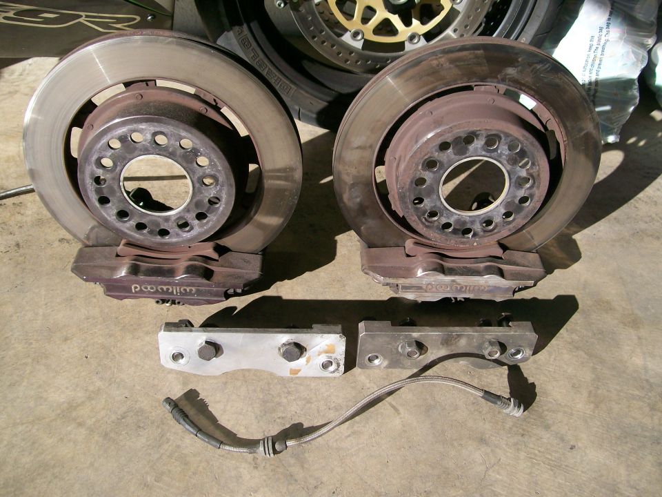Two brake rotors with calipers and mounting brackets, one brake line