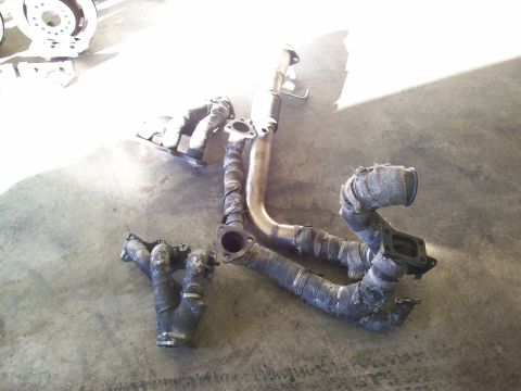 1995 Ford Probe - Exhaust manifold and catalytic converter assembly with heat wrap, lying on a concrete floor.
