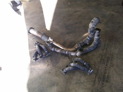 1995 Ford Probe - Exhaust manifold and pipe components are laid out on a concrete surface, with a watermark for Supermotors.net visible.