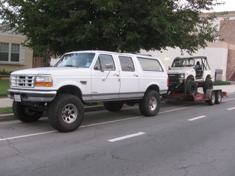 1987 Suzuki Samurai - A lifted 1987 Suzuki Samurai is transported on a trailer behind a white Ford Bronco.