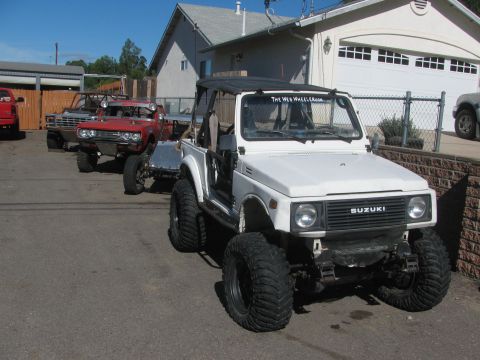 1987 Suzuki Samurai - Modified 1987 Suzuki Samurai with prominent off-road tires and a web address on the windshield.