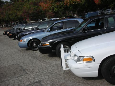 2004 Ford Crown Victoria - Multiple Ford Crown Victoria police cars are lined up in a parking lot.